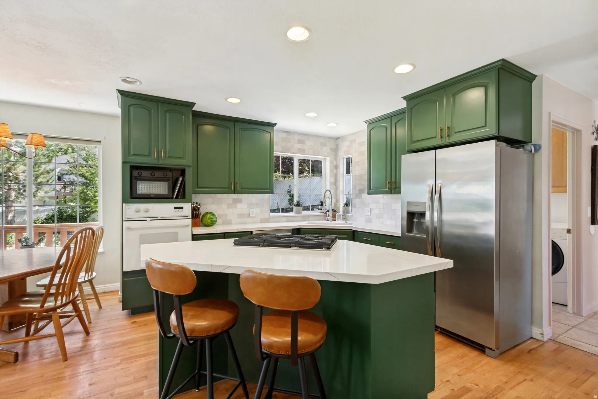 Kitchen featuring green cabinetry and a white countertop island with integrated cooktop