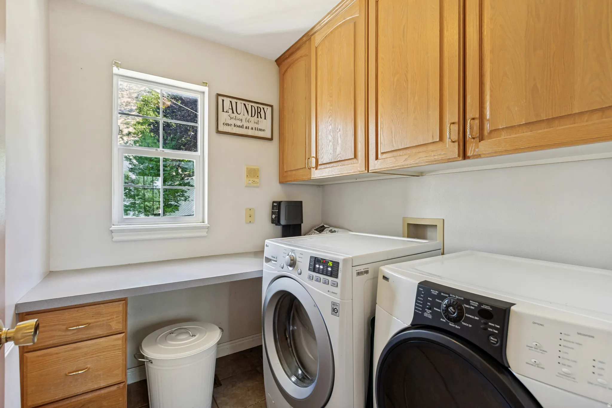 Laundry area featuring a large window, light wood cabinetry, and a light-toned countertop