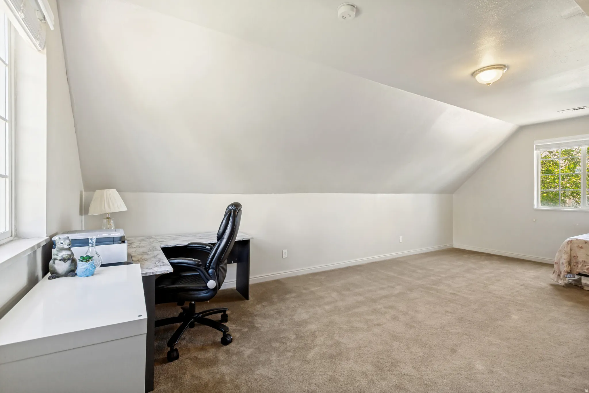 Carpeted room with a pitched ceiling and neutral wall tones