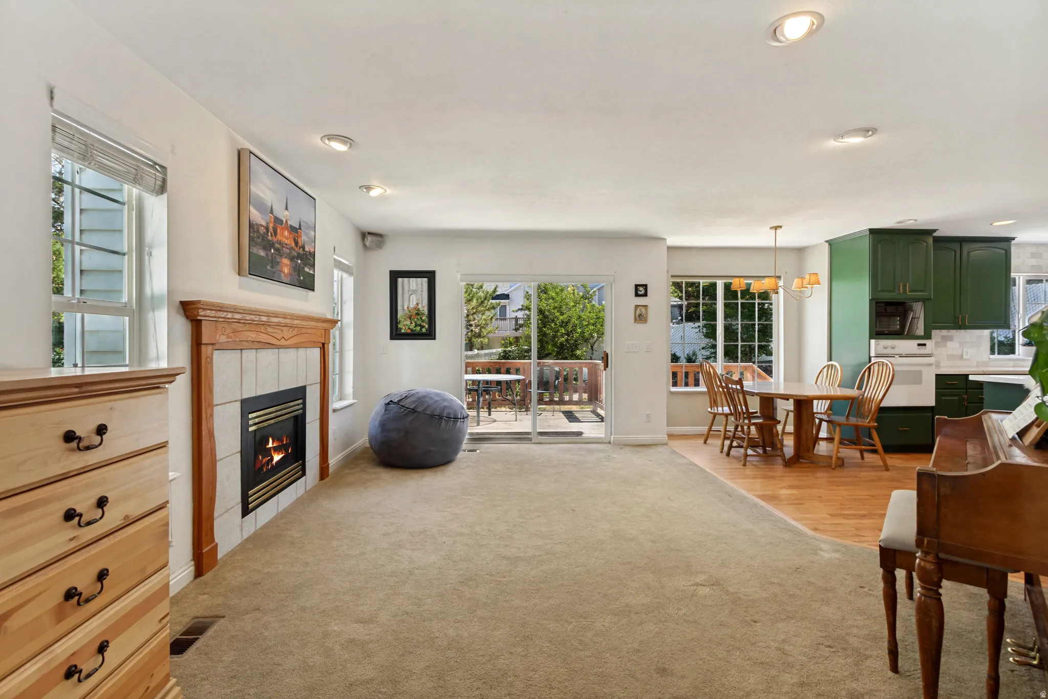 Open-concept living area with a wood-mantled fireplace, sliding glass door to an outdoor deck, and recessed lighting