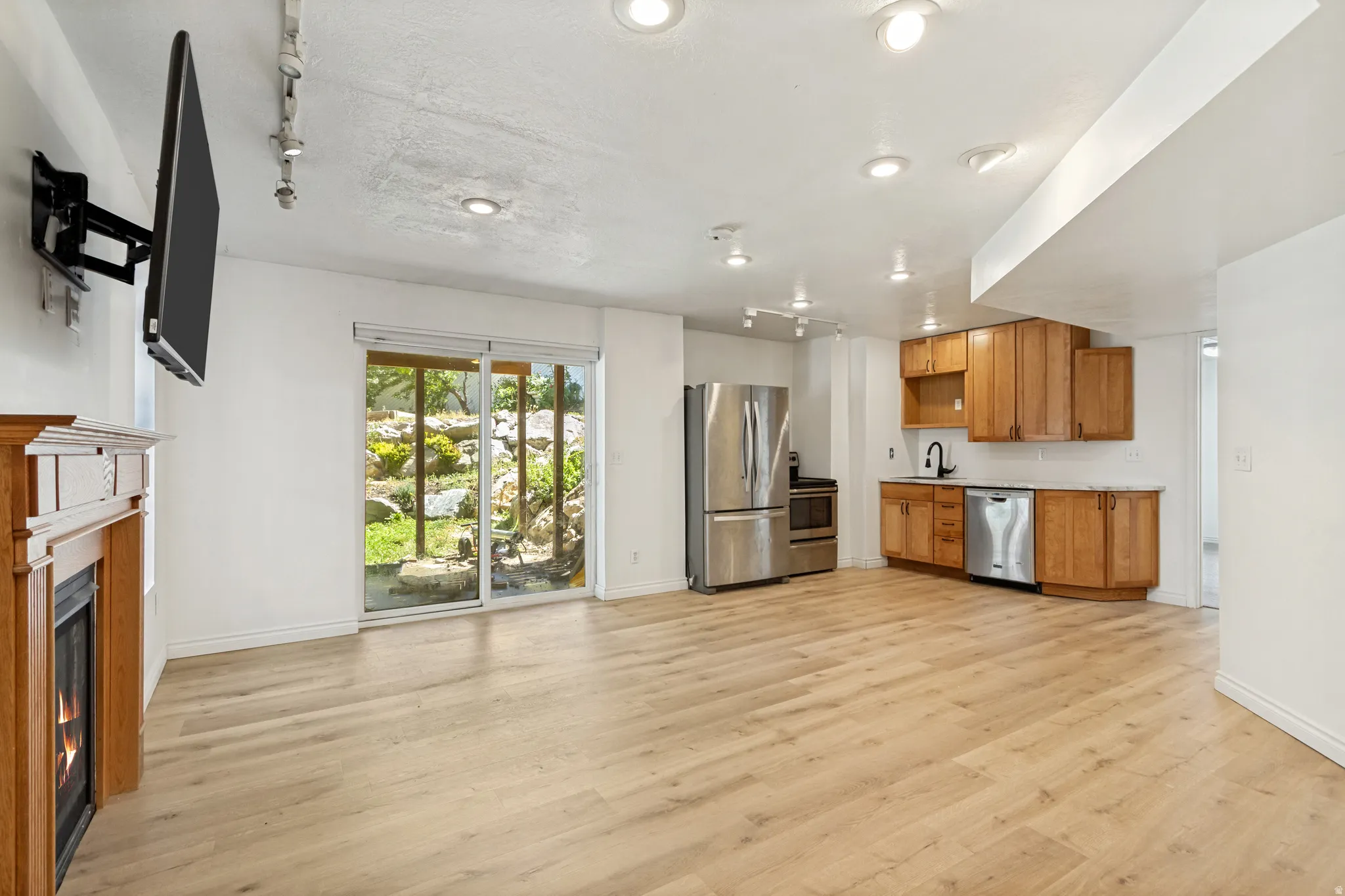 Open-concept living area featuring wood-finish flooring, a built-in fireplace with a wood mantel, and sliding glass doors