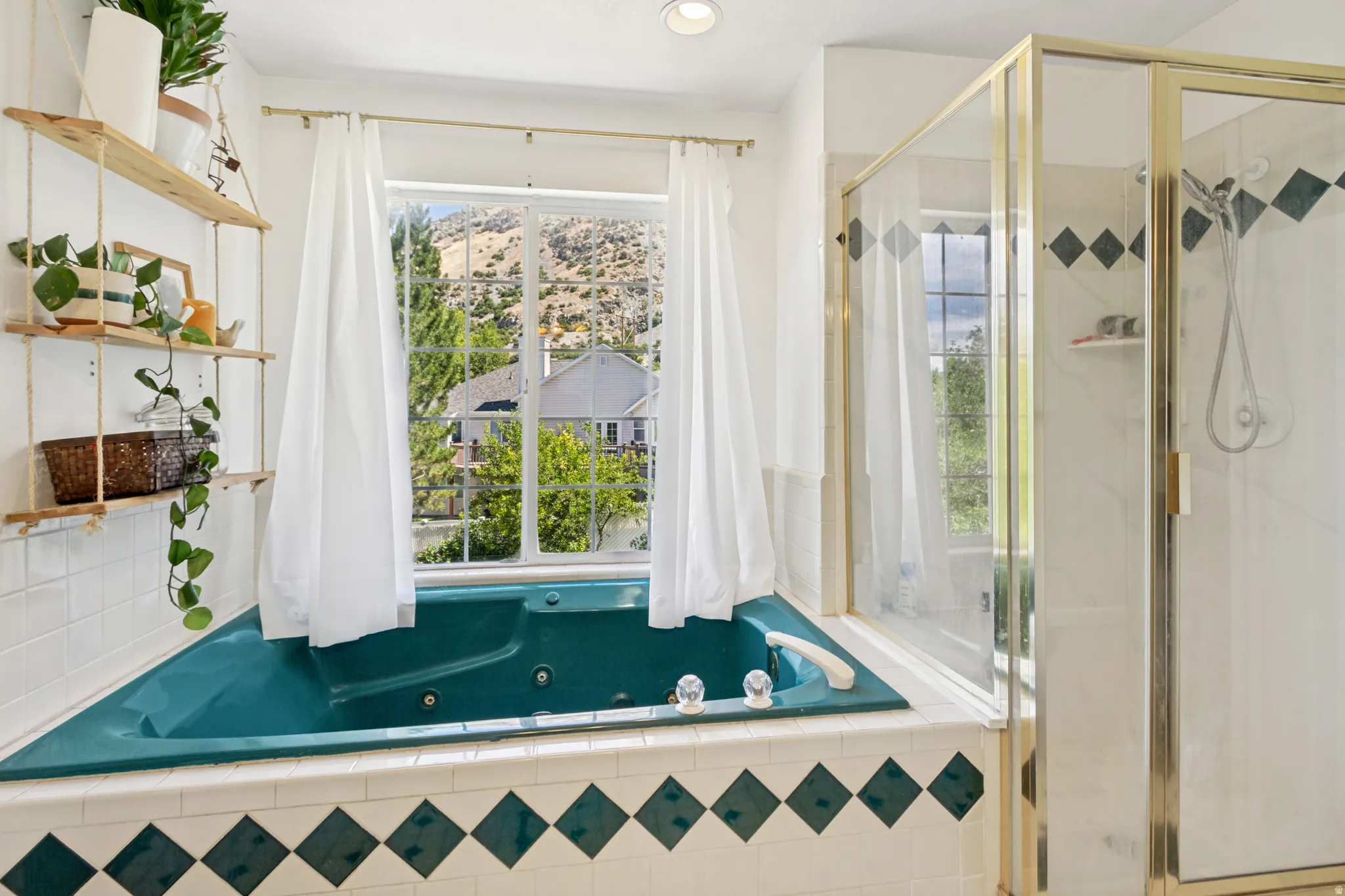 Deep soaking tub with jets, framed by a window with mountain and greenery scenery