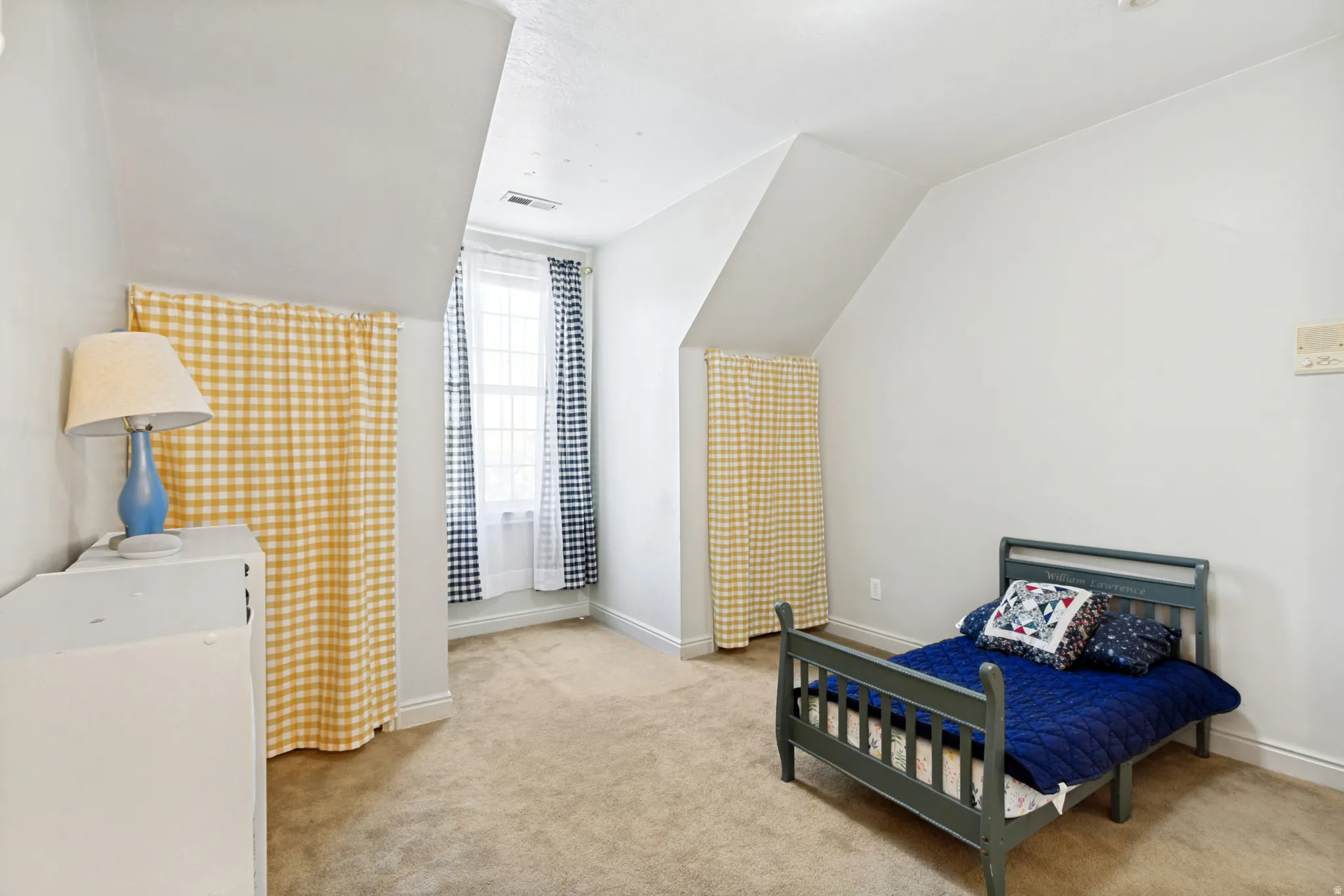 Carpeted room featuring sloped ceilings, a window with muntins, and ample floor space