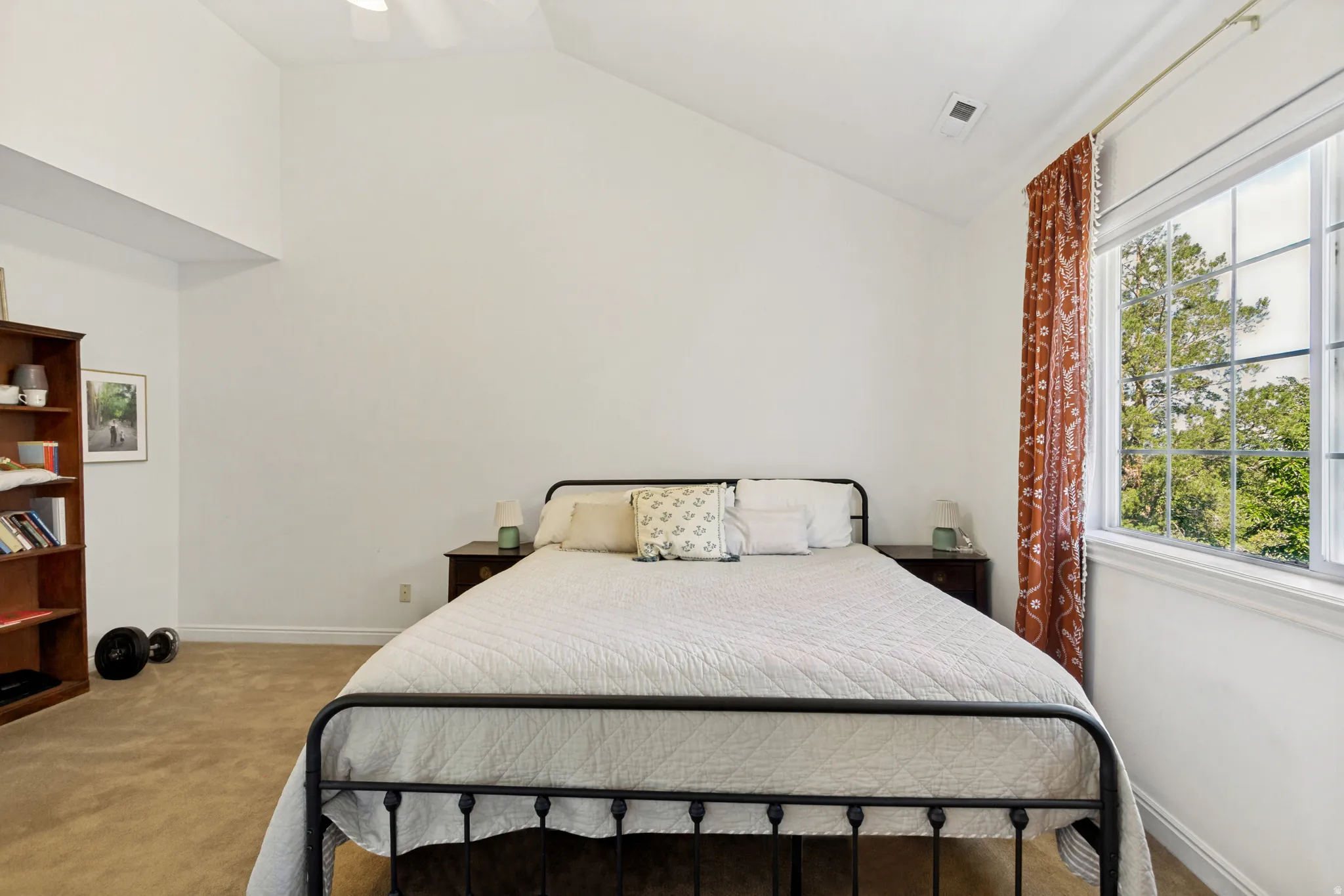 Carpeted room featuring a vaulted ceiling and a large window with white muntins