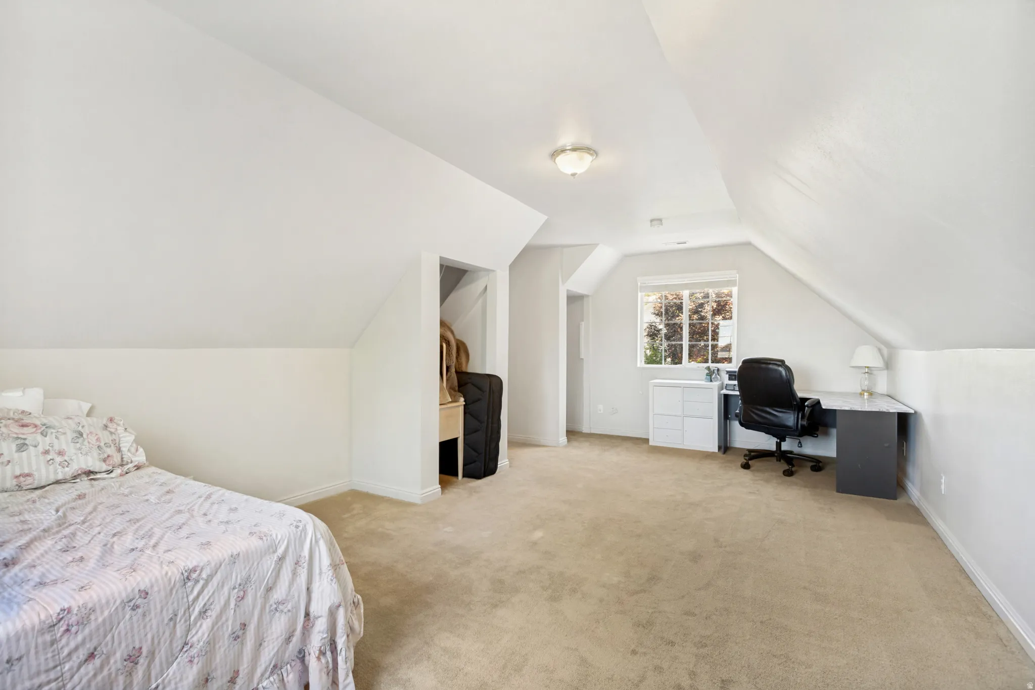 Carpeted room with sloped ceilings and recessed window