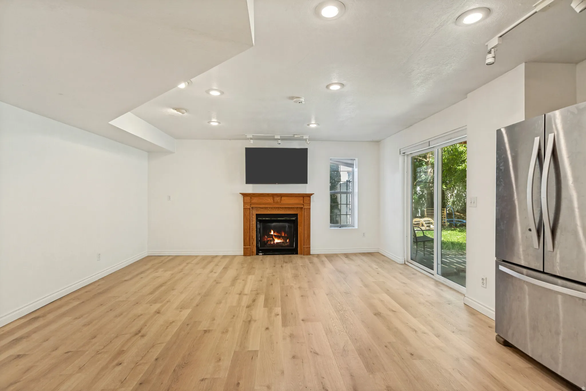 Spacious room featuring wood-finish flooring, a fireplace with a wood mantle, and sliding glass doors to the exterior