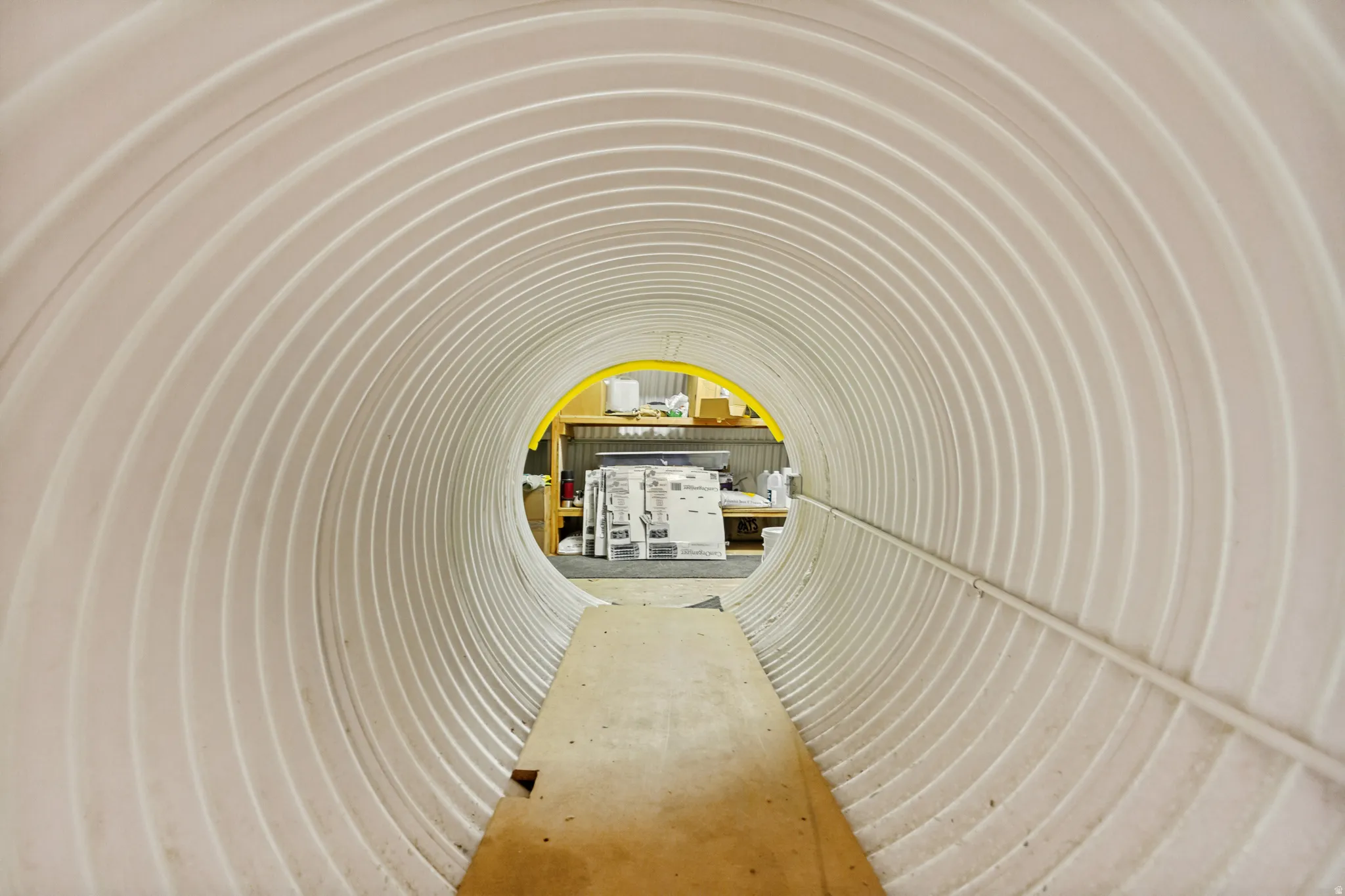 Corrugated white tunnel with a light wood plank floor