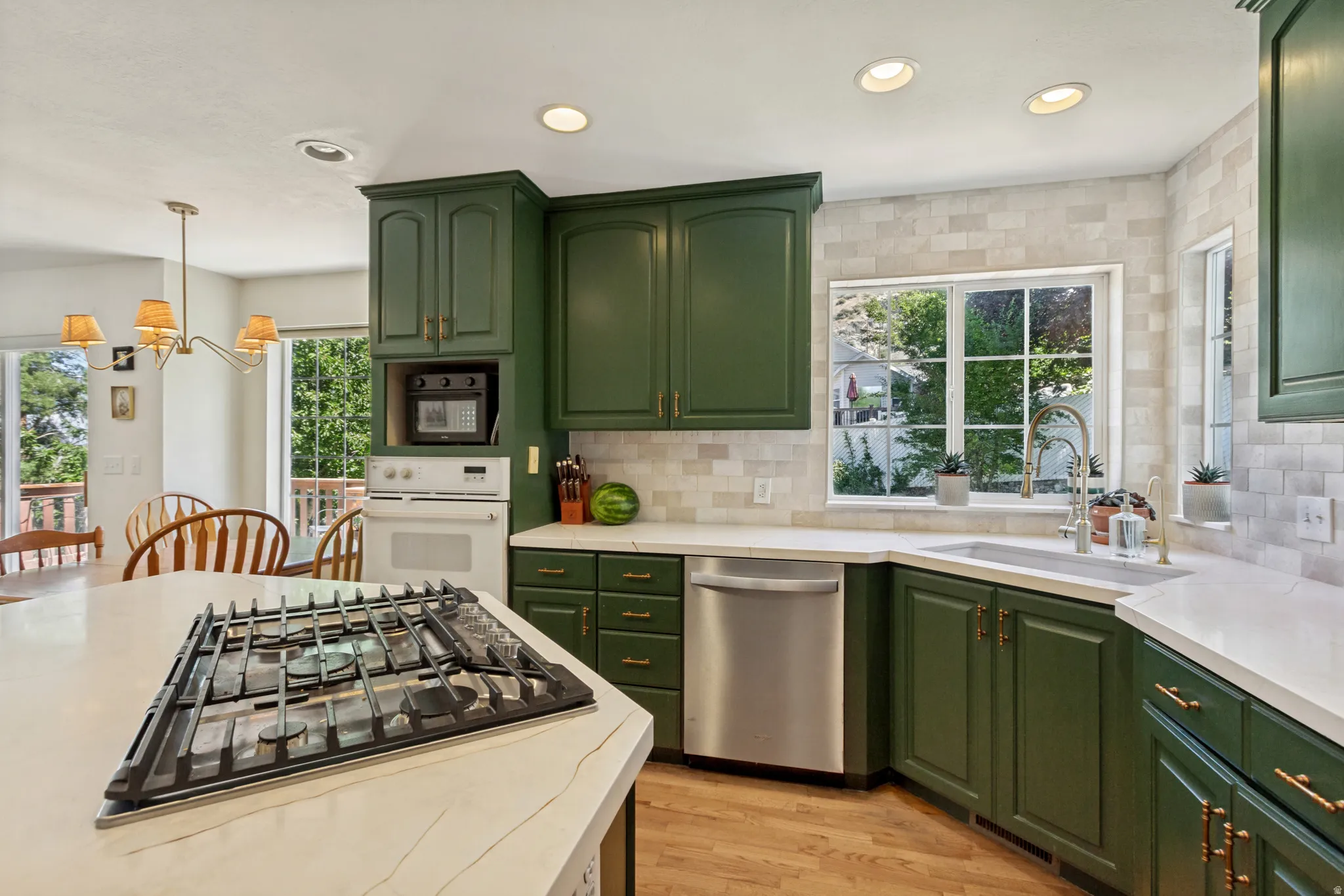 Kitchen featuring green cabinetry, white countertops, built-in gas range, stainless steel dishwasher, and a tile backsplash