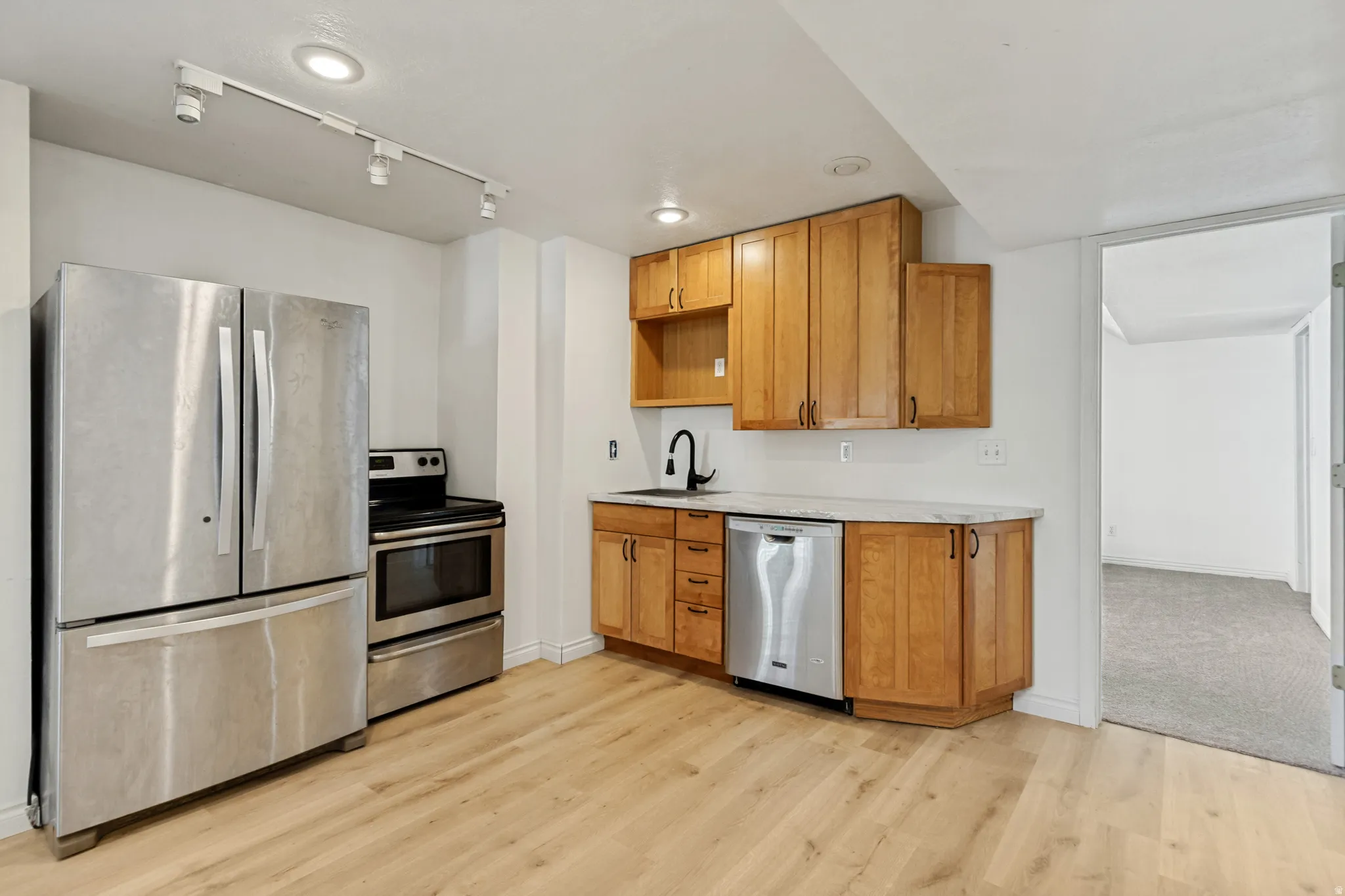 Kitchenette featuring stainless steel appliances, wood-finish cabinetry, and light-toned countertops