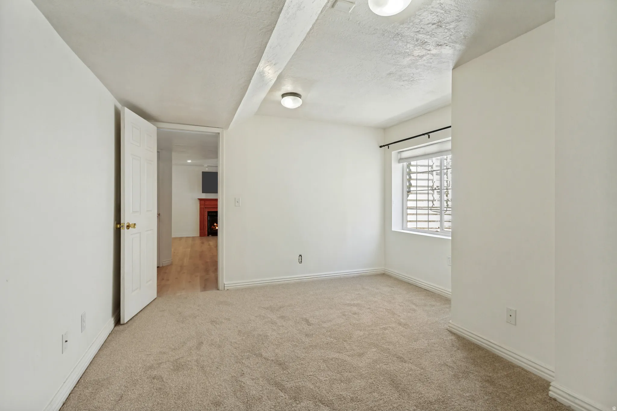 Carpeted room with white walls, baseboards, and a window featuring horizontal blinds