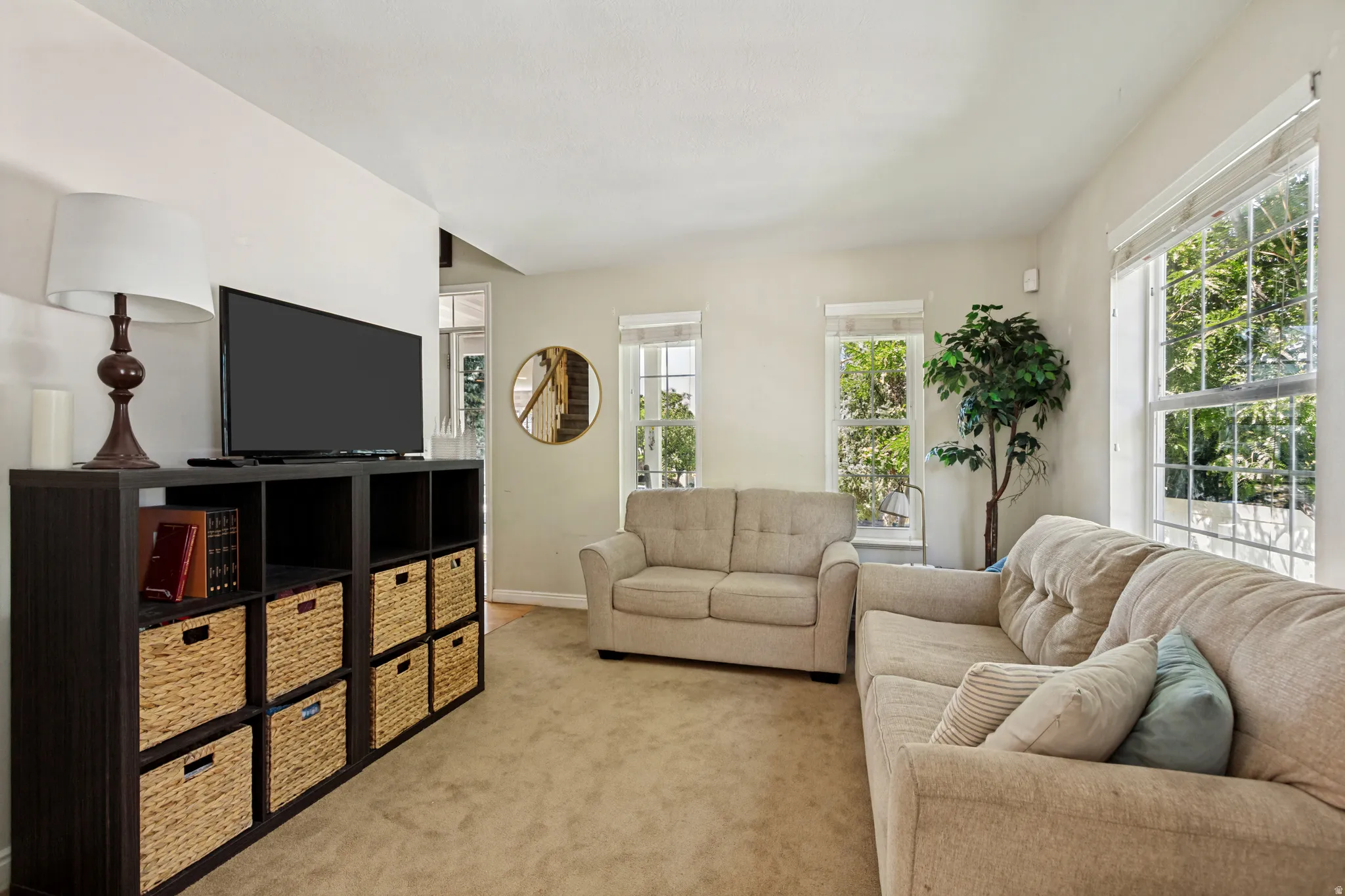 Bright living area featuring multiple windows, a neutral color palette, and carpeted flooring