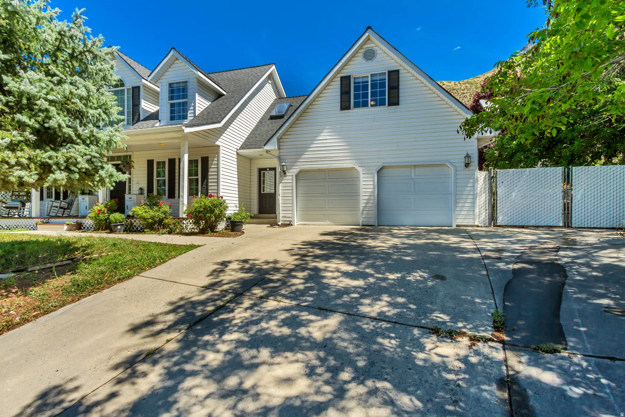 White siding exterior with a two-car garage, a covered porch with white columns, and black window shutters