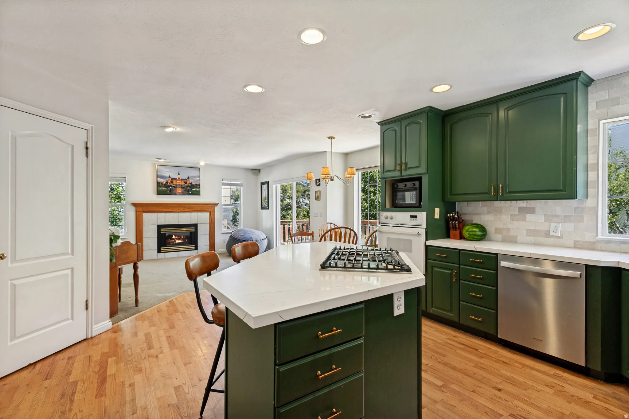 Kitchen featuring green cabinetry, stainless steel appliances, a white tile backsplash, and light-colored countertops