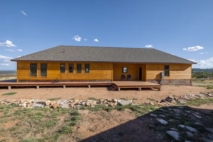 Wood-sided exterior with multiple windows, a composite deck, and a shingle roof