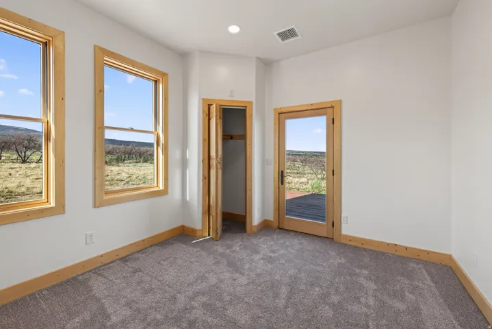 Two large windows with wood frames, wood-finish trim, a recessed ceiling light, and a glass-paneled door with a wood frame leading to an outdoor deck