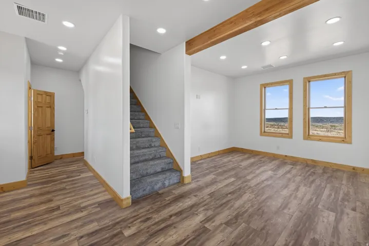 Recessed ceiling lighting, wood-finish flooring, wood trim, dual windows, and an exposed wood beam