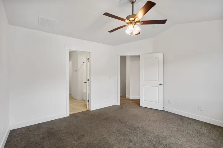 Carpeted room featuring a vaulted ceiling with a ceiling fan and light fixture