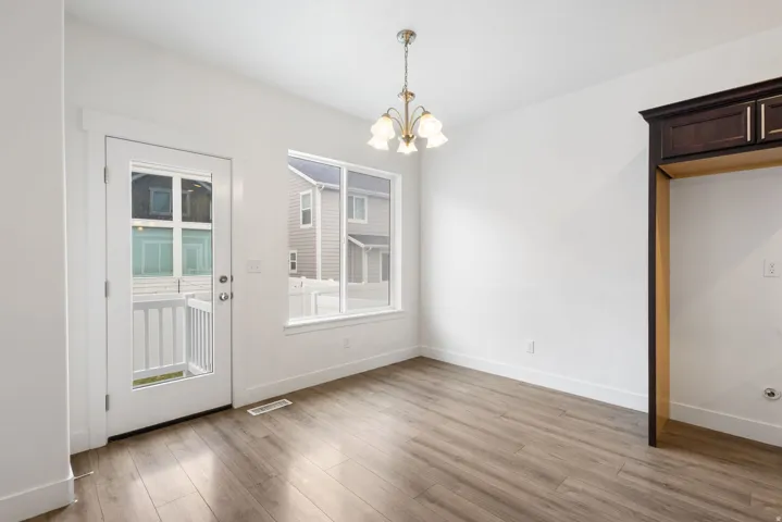 Dining area featuring wood-finish flooring, a contemporary chandelier, and a large window