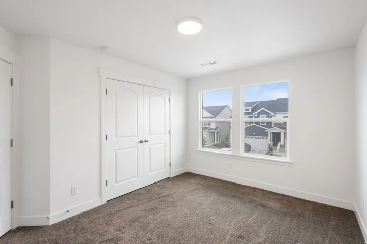 Bright interior space featuring dual windows, neutral carpeting, and a flush-mount ceiling light