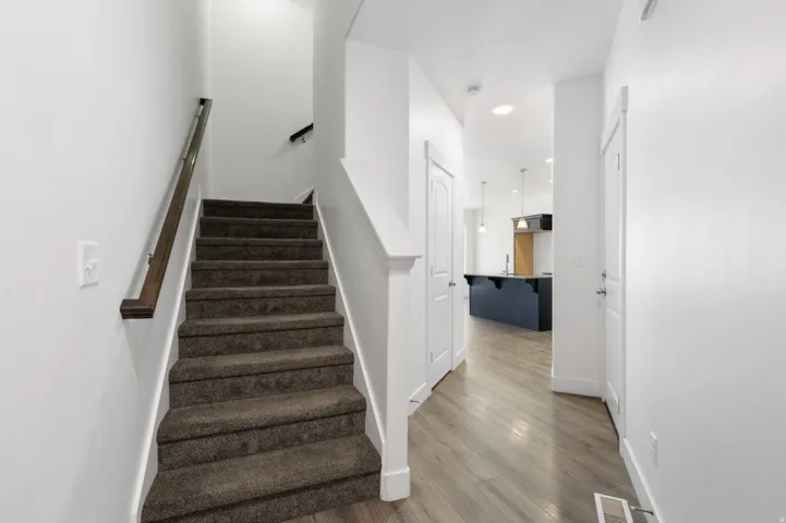 Carpeted staircase with dark wood-finish handrail