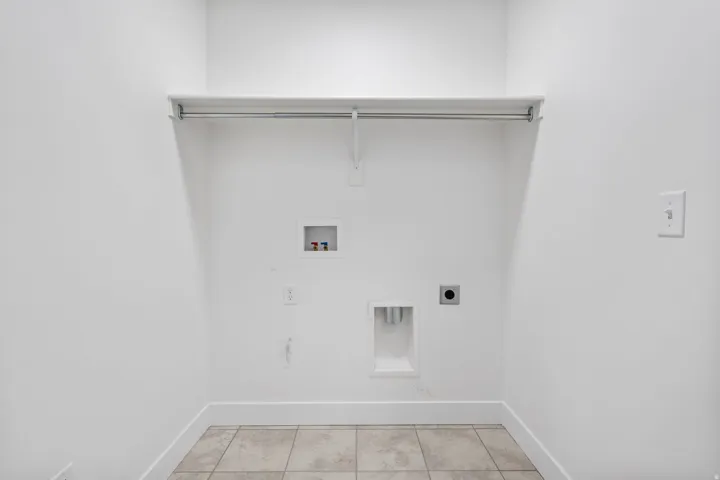 Dedicated laundry area featuring a neutral tile floor, white walls, and a built-in hanging rod