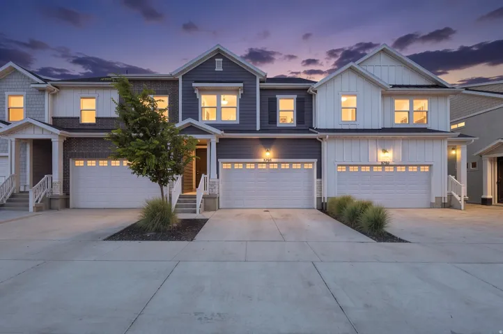 Contemporary townhome-style residences featuring varied siding finishes, white trim accents, individual garages, private entryways, and concrete driveways
