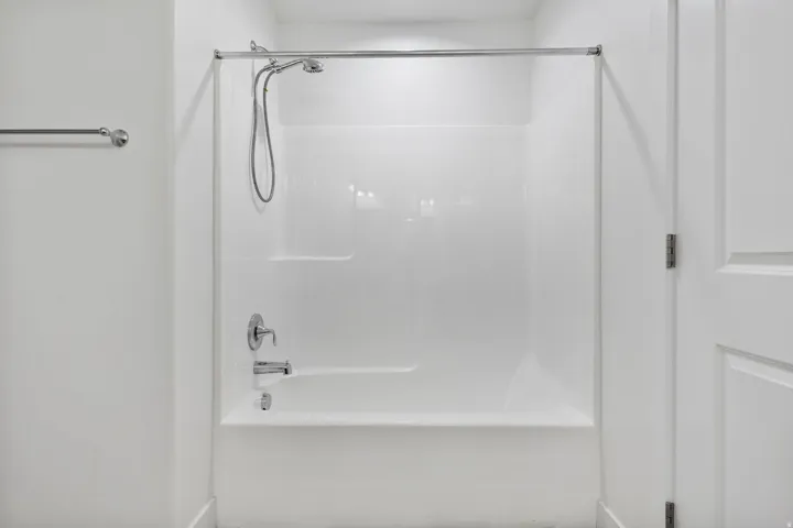 Tub and shower combination unit featuring a chrome shower head with a handheld option, a single-handle faucet, and an integrated soap dish