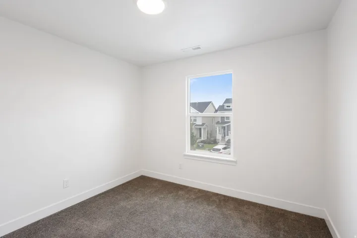 Room featuring a single window, white walls, and dark gray carpeting