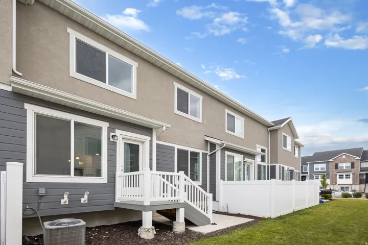 Rear exterior featuring a private deck, sliding glass door entry, and white privacy fencing