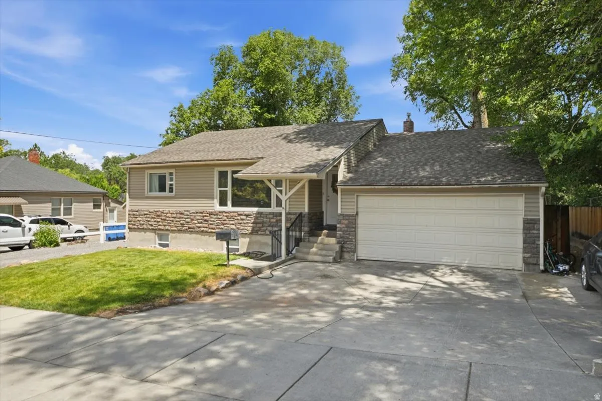 Exterior featuring horizontal siding with stone veneer accents, a shingle roof, and an attached two-car garage