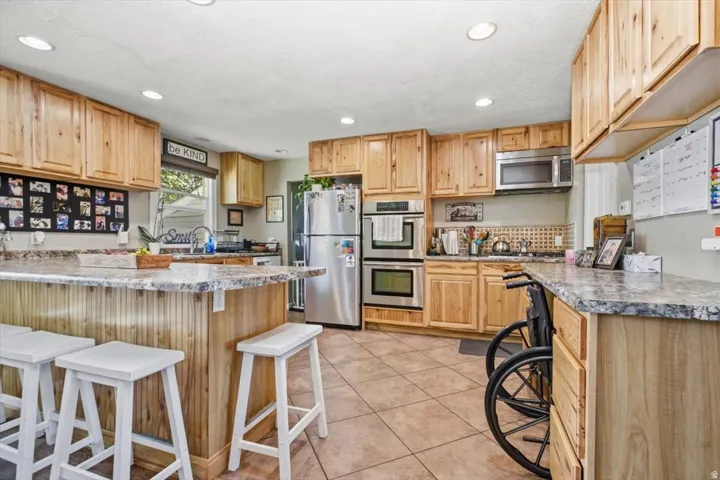 Kitchen featuring wood cabinetry, stainless steel appliances, a double oven, and recessed lighting