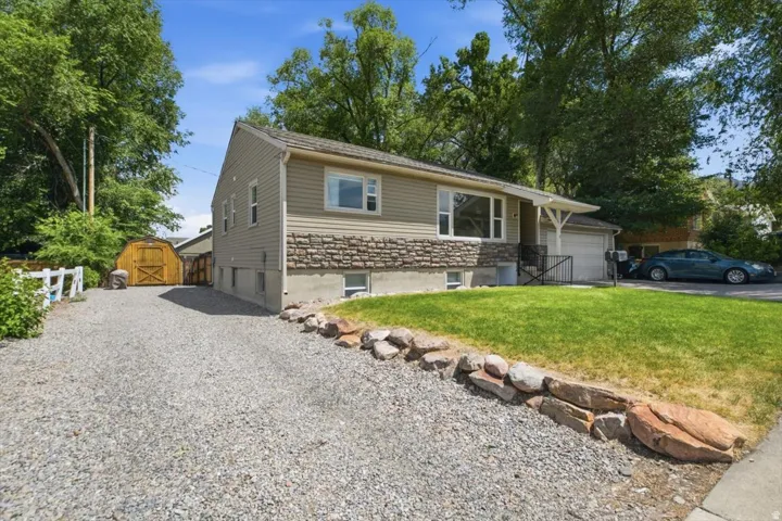 Split-level residence featuring tan siding and a stone facade
