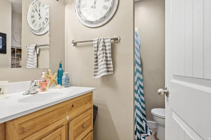 Bathroom vanity featuring a single-basin sink, chrome faucet, and light wood-finish cabinetry