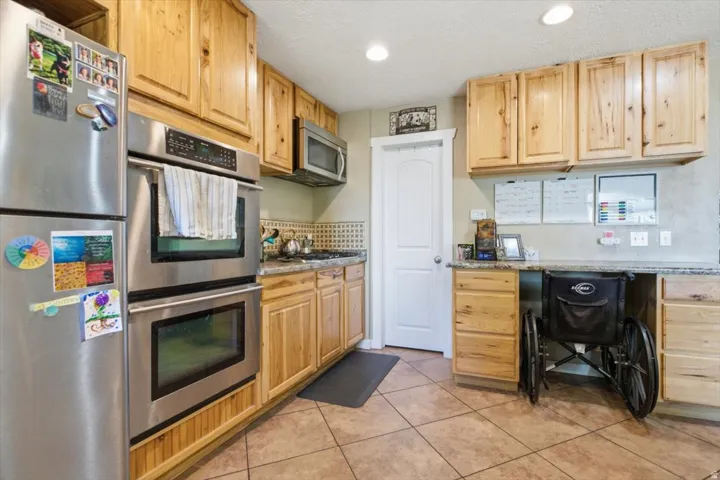 Kitchen featuring light wood cabinetry, stainless steel double wall ovens, a tiled backsplash, and recessed lighting