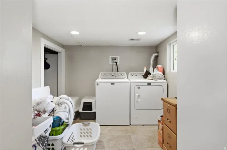 Utility area featuring a washer and dryer, recessed lighting, a window, and tiled flooring