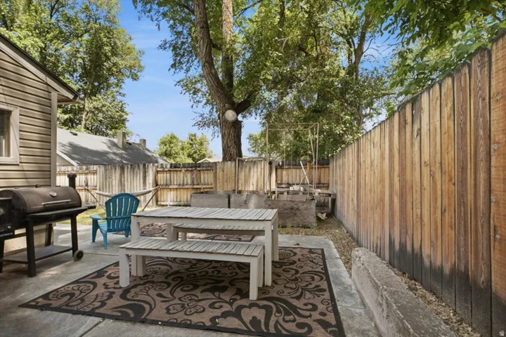 Expansive concrete patio with mature trees and a privacy fence