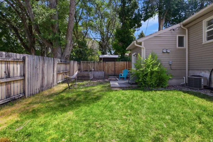 Expansive backyard featuring a manicured lawn, established trees, and a full privacy fence