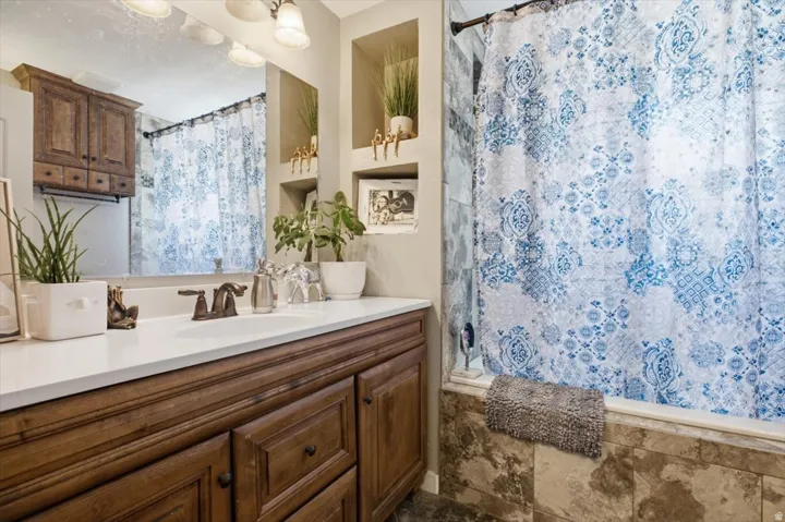 Bathroom vanity featuring a single basin, bronze-finish faucet, and a large mirror
