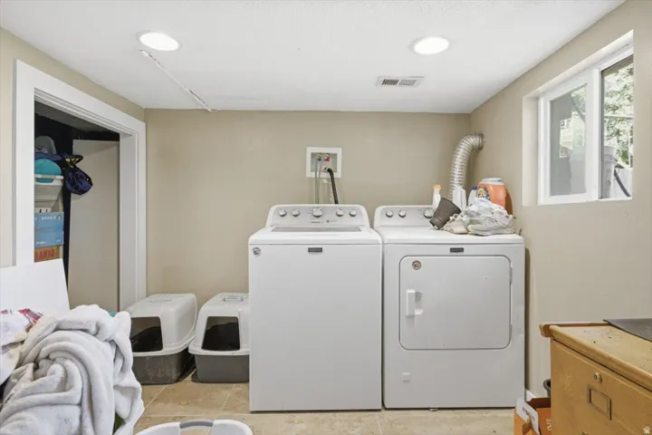 Dedicated laundry area with tile flooring, a window offering natural light, and recessed ceiling lighting