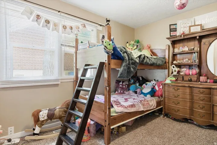 Bedroom featuring light beige wall paint, wood-finish bunk beds, and a wood-finish dresser with an attached mirror