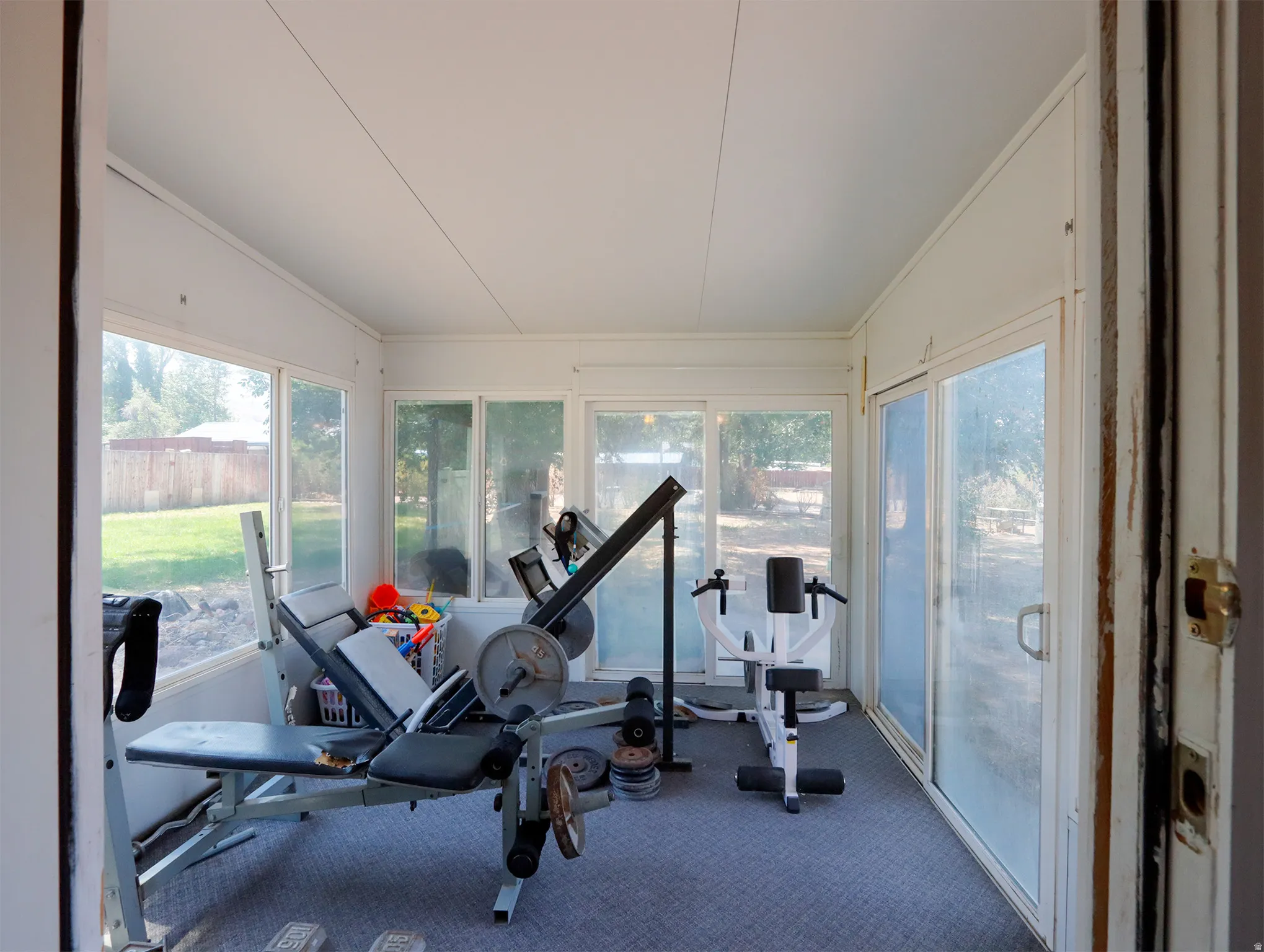 Enclosed sunroom featuring multiple large windows, a sliding glass door, and carpeted flooring