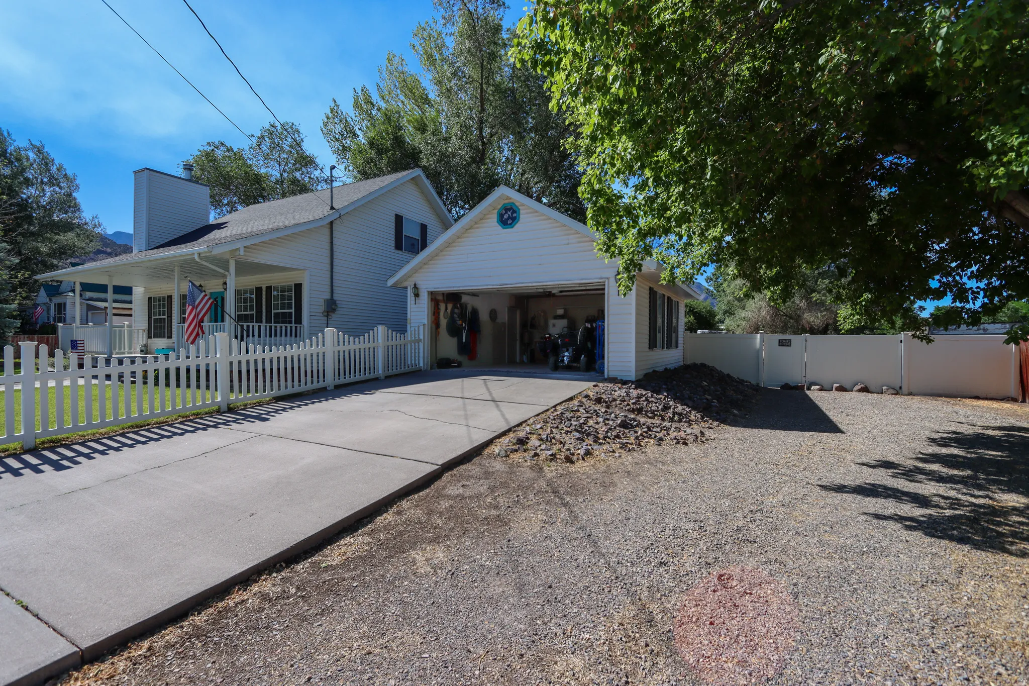 White siding exterior with a covered front porch and a detached two-car garage