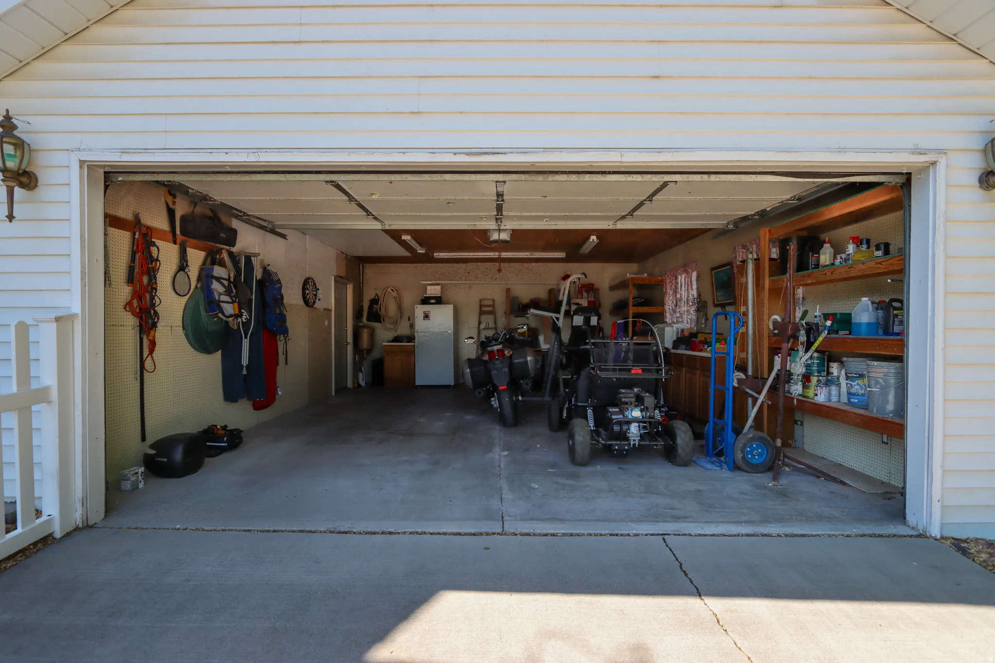 Two-car garage with a concrete floor, overhead lighting, and built-in shelving