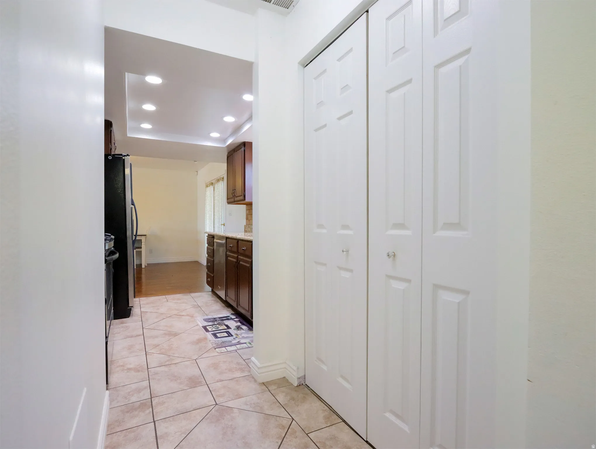 Hallway featuring light-toned square and diamond pattern tile flooring, white walls, and bi-fold panel doors