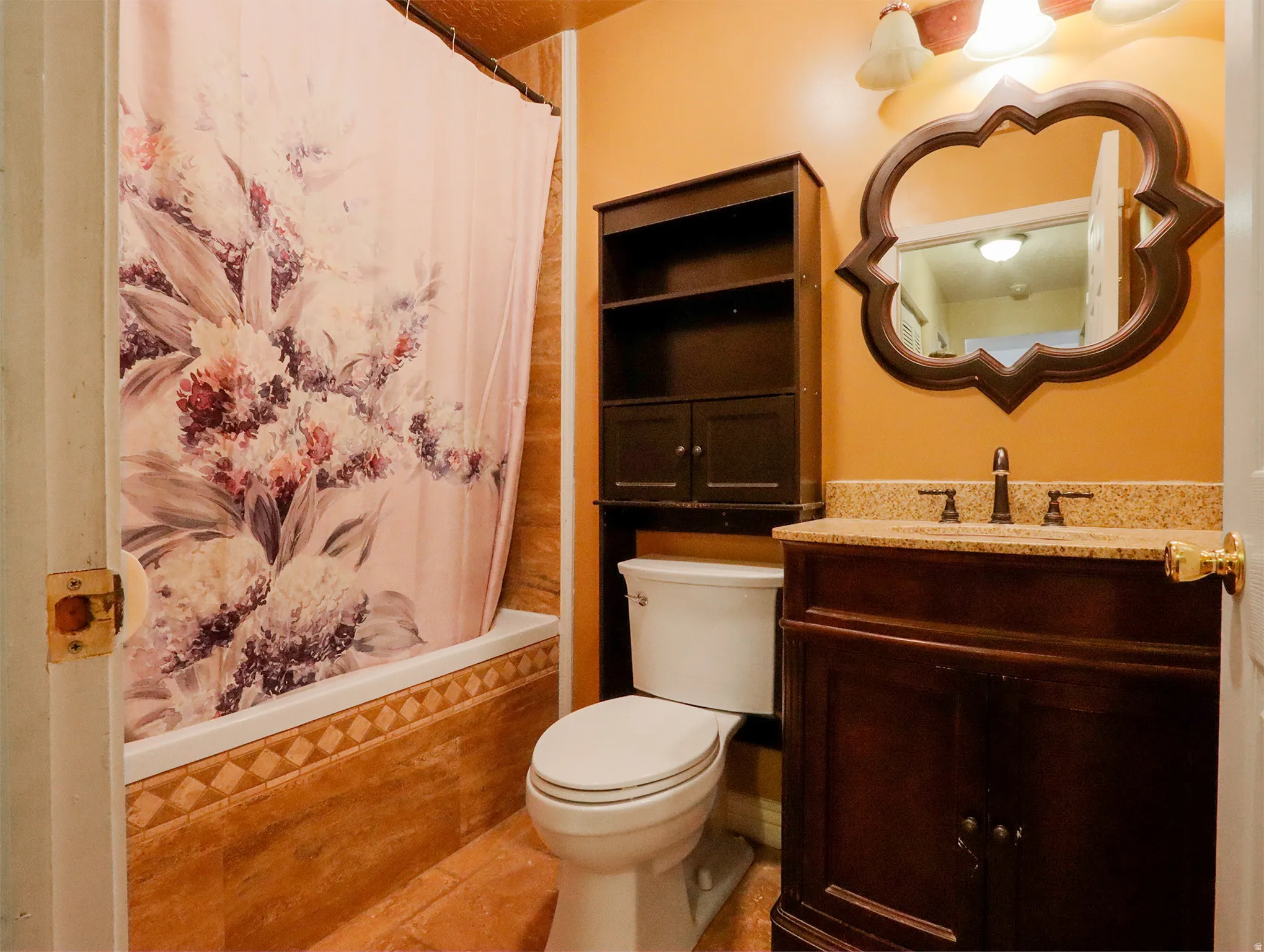 Bathroom featuring a built-in tub with tile surround, a dark wood vanity with a light-toned countertop, a mounted mirror, and an overhead lighting fixture