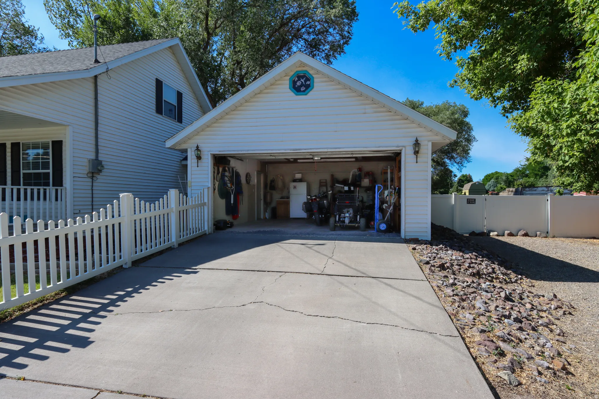 Detached garage with white siding, concrete driveway, and exterior lighting fixtures