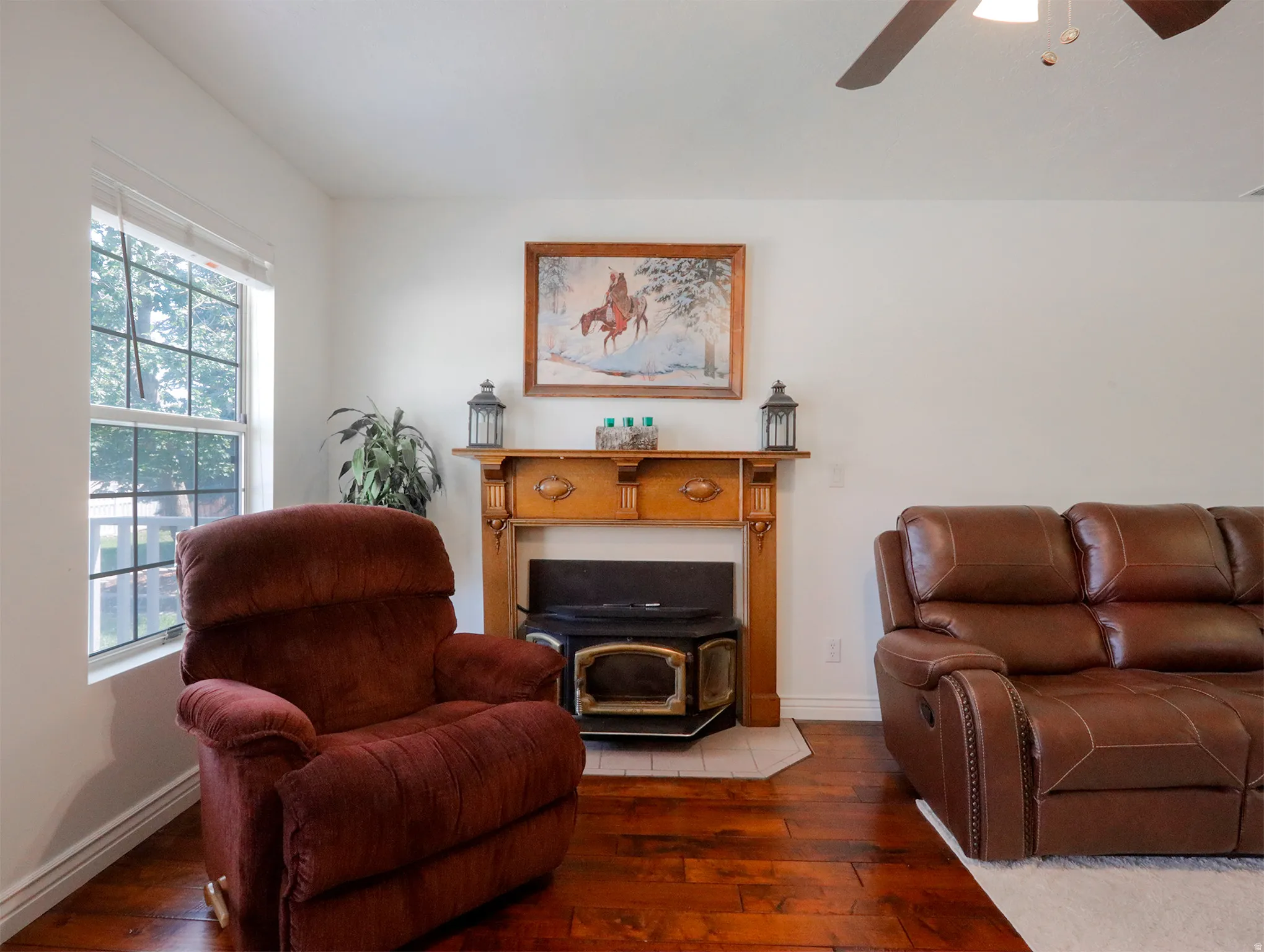 Living area featuring warm wood flooring, a decorative wood mantel, and a built-in wood-burning stove