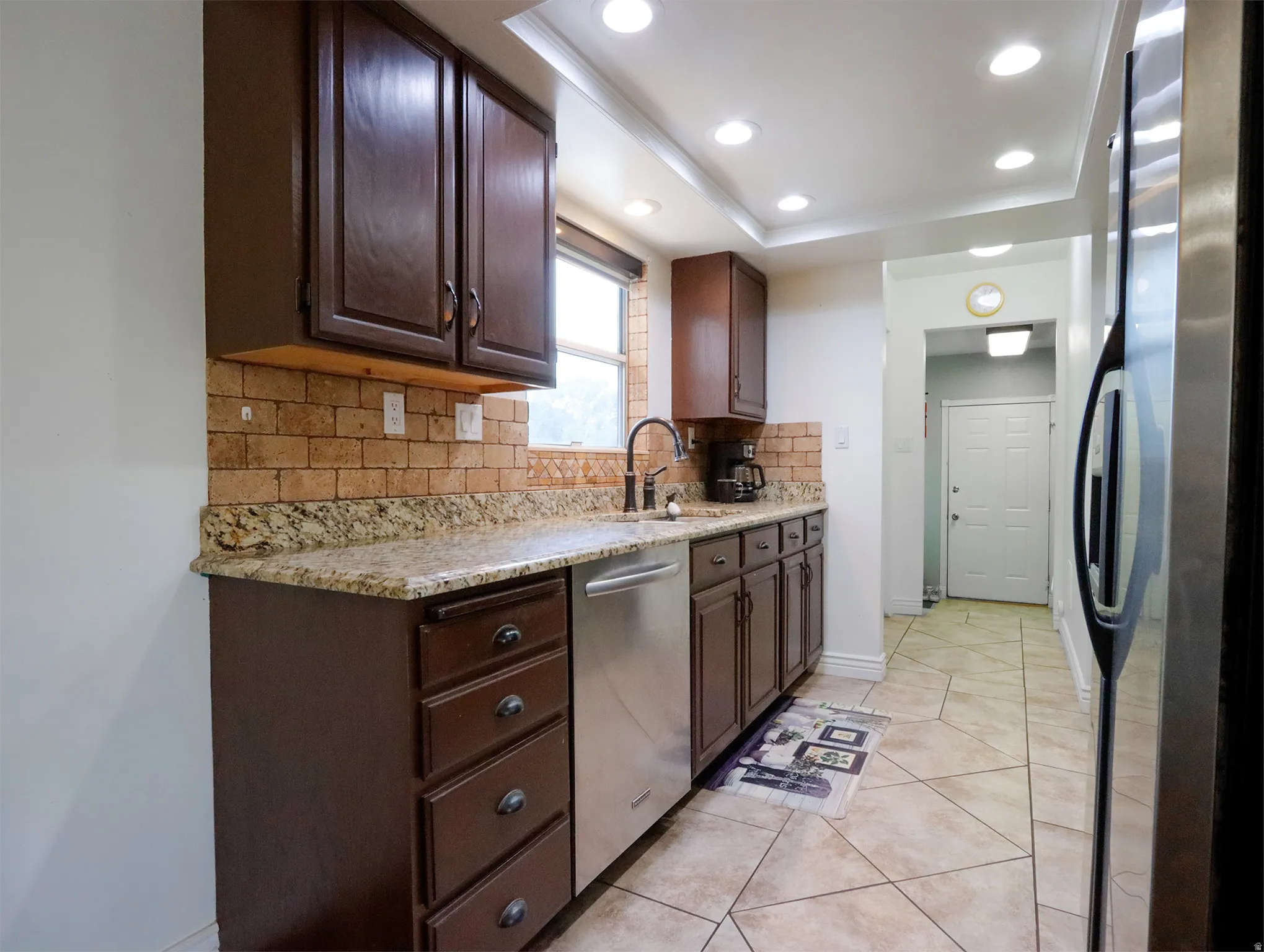 Kitchen featuring dark wood cabinetry, granite-finish countertops, and a brick-patterned tile backsplash