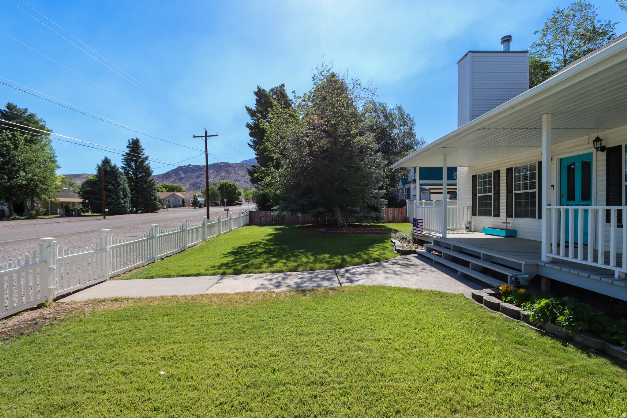 Front exterior featuring a white picket fence, covered porch, and vibrant turquoise entry door
