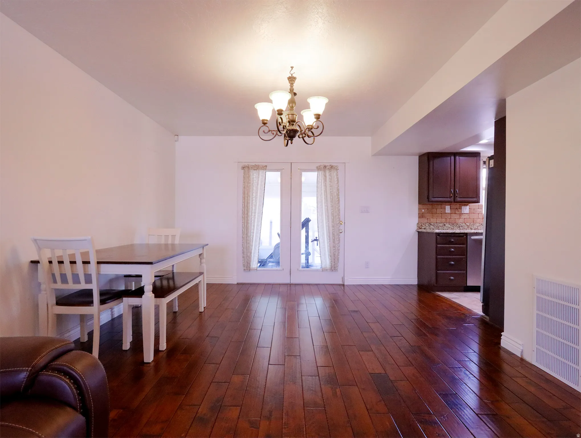 Open-concept living area with dark wood-finish flooring, white walls, and a chandelier